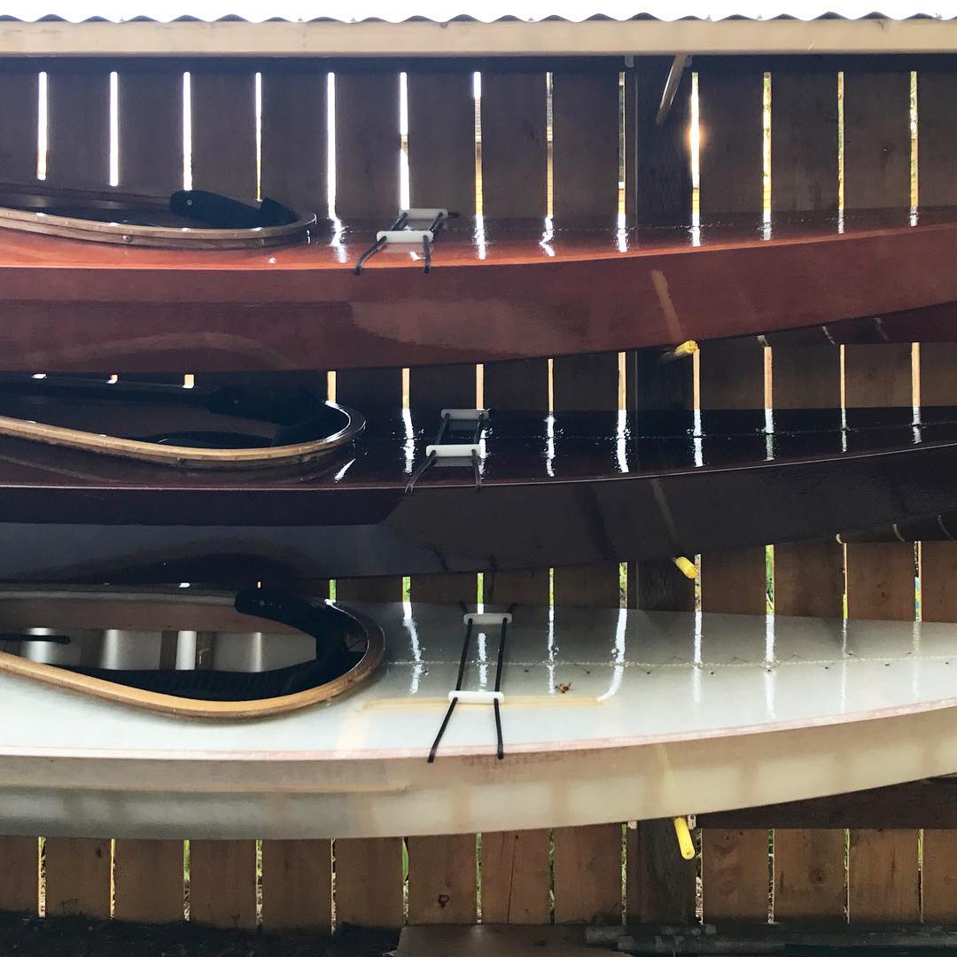 three skin on frame kayaks mounted on a fence