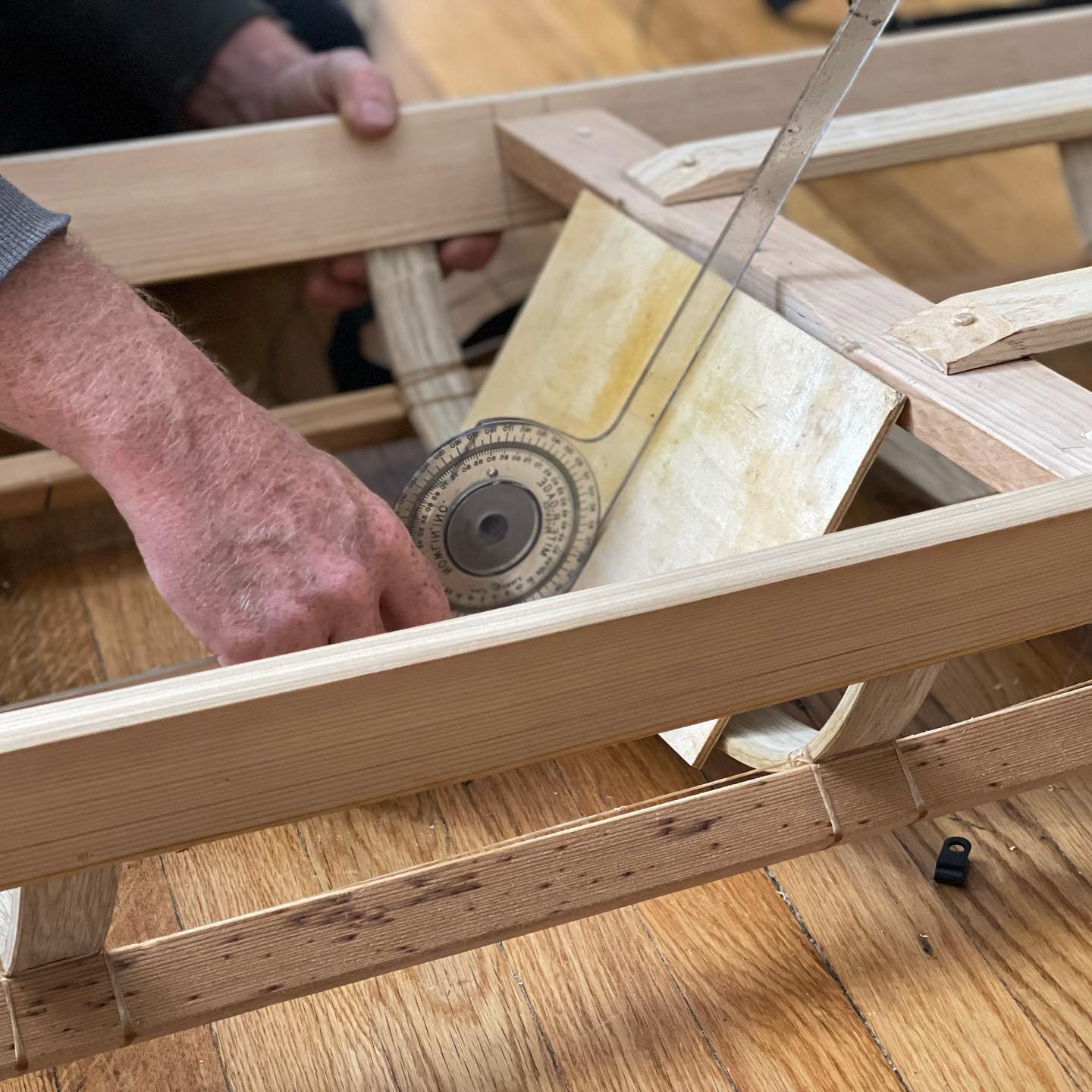 photo of hands holding a tape measure and taking a measurement on a kayak frame