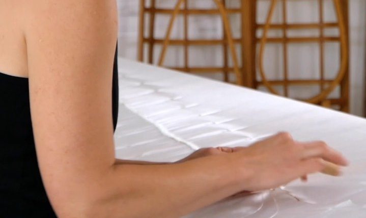 woman sewing a nylon skin onto a kayak frame
