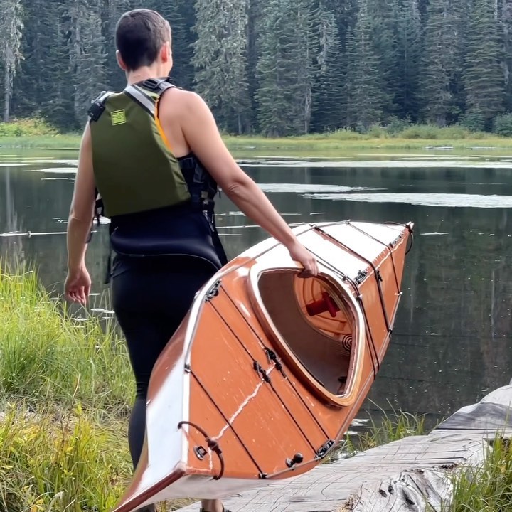 woman carrying an F1 skin on frame kayak with one hand