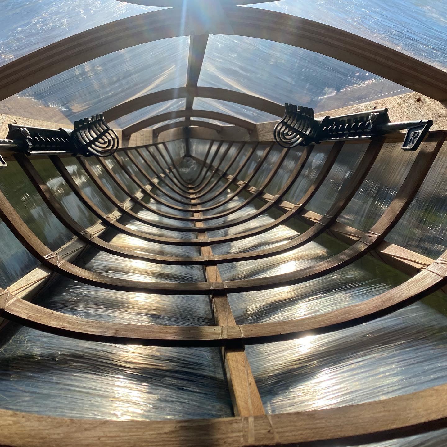 a skin on frame kayak wrapped in clear plastic for testing