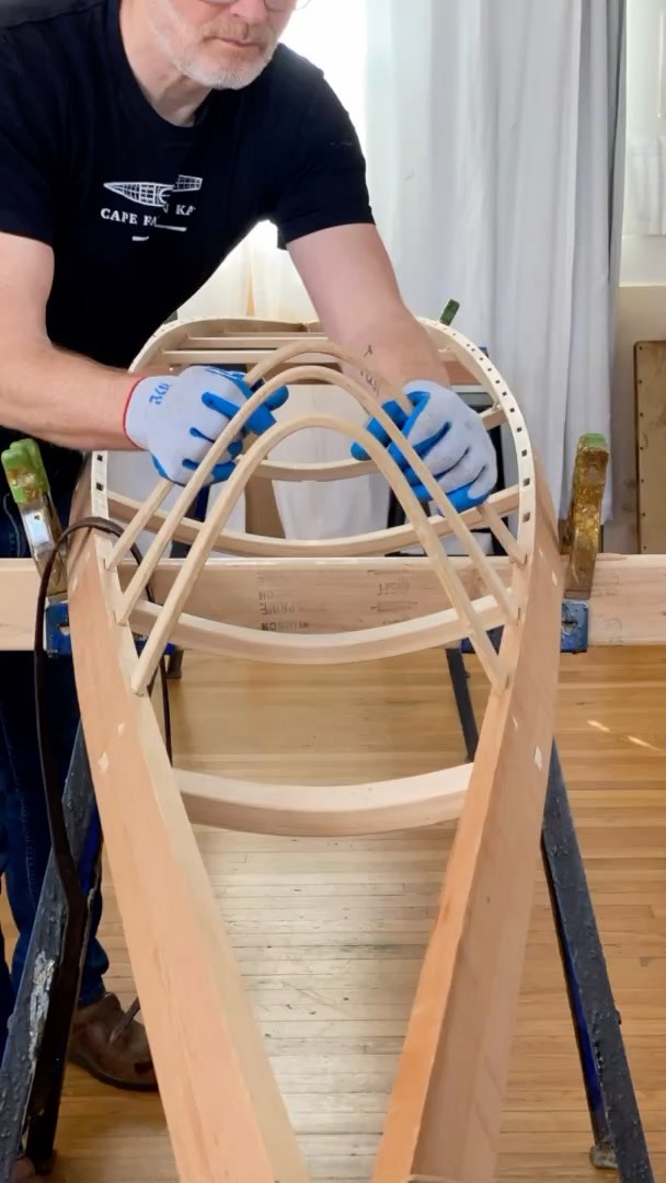 man steam bending ribs into a kayak frame