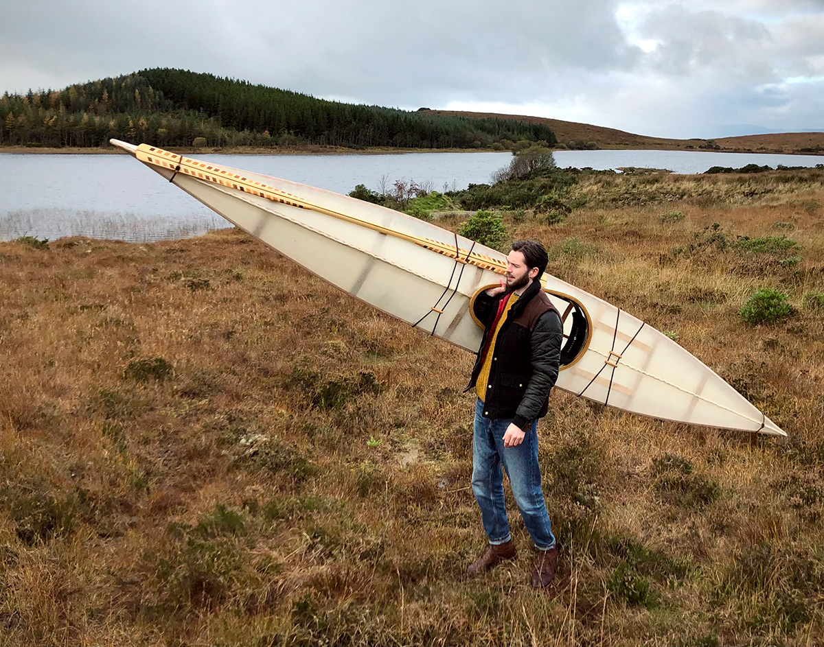 man carrying a lightweight skin on frame F1 kayak on one shoulder