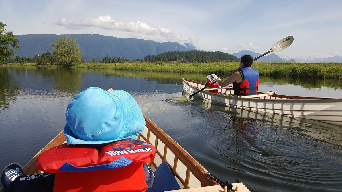 family paddling a pair of skin on frame canoes