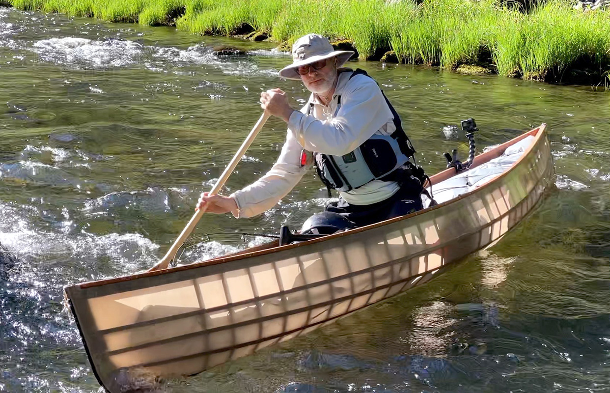 man running a river in a skin on frame solo canoe