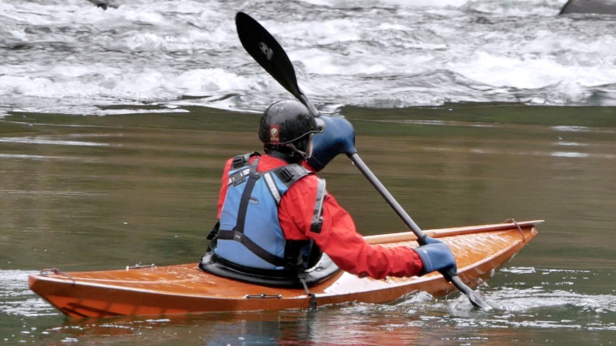 kayaker paddling a skin on frame whitewater kayak