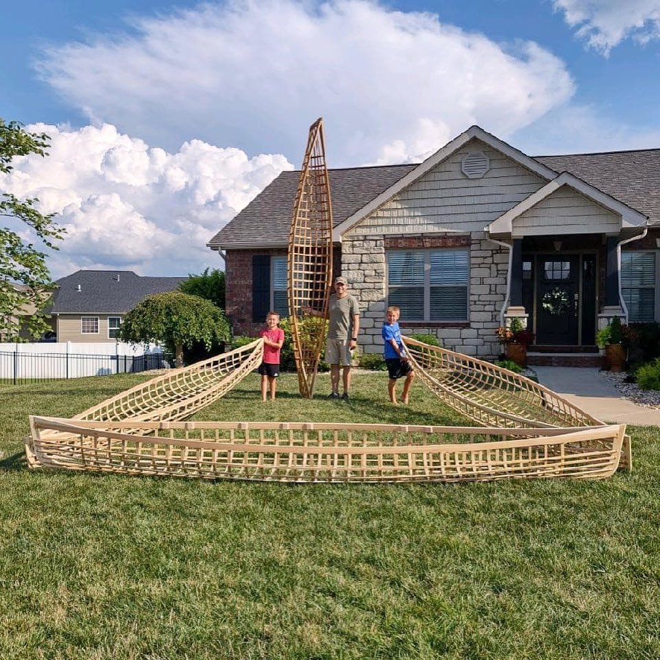 Dad and two kids displaying the four canoe frames they built