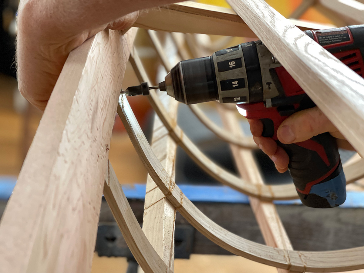 detail of hands using a power drill on a kayak frame
